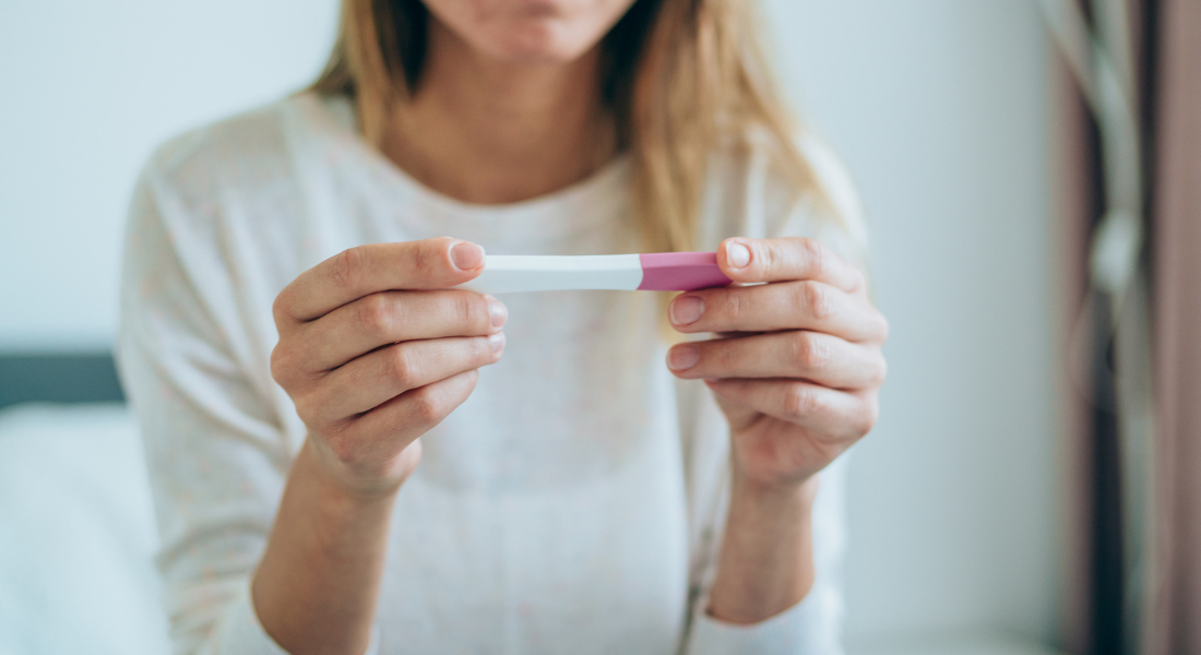 Woman in perimenopause looks at pregnancy or fertility test. Fertility and perimenopause are more linked than you think.
