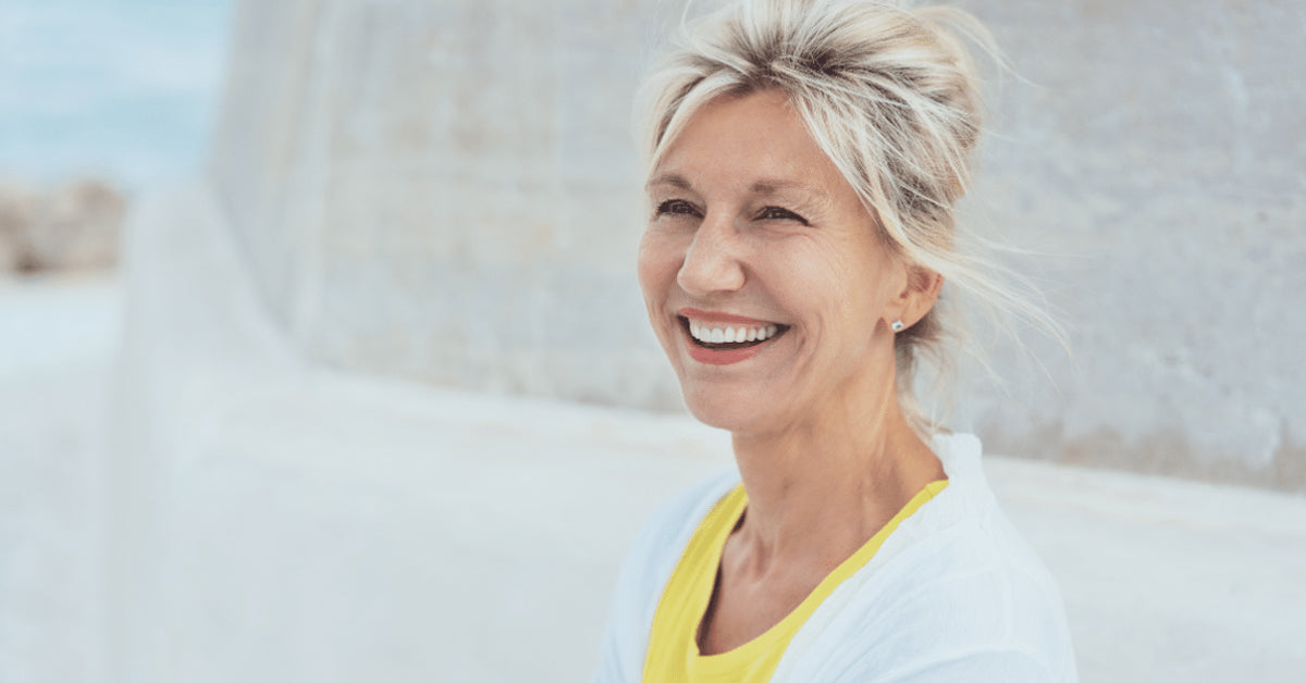Woman in her 50s smiling:  Menopause can affect your mouth, teeth and gums. Learn about dry mouth, gum disease, burning mouth, cavities and other oral health changes.